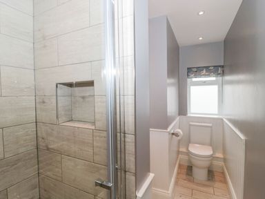 A bathroom with a toilet and a shower with tiled walls at The Anchorage in Bournemouth