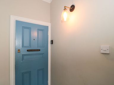 An entrance door painted blue with a wall light and light switch at The Anchorage in Bournemouth