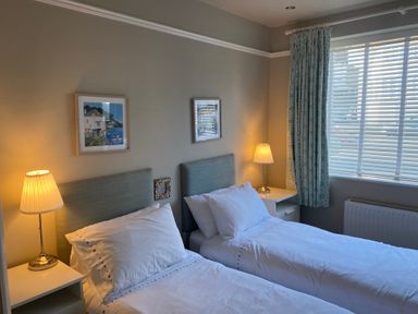 A bedroom with two single beds side by side each with a lamp on a bedside table at The Anchorage in Bournemouth