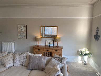A living room with a wooden sideboard with two lamps and a mirror above it at The Anchorage in Bournemouth