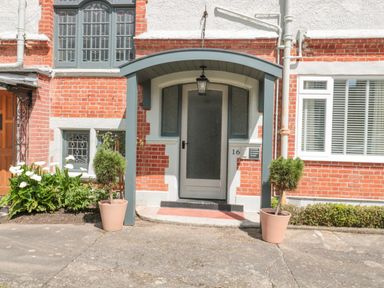 An entrance door with glass panels under a porch with two potted plants on each side at The Anchorage in Bournemouth