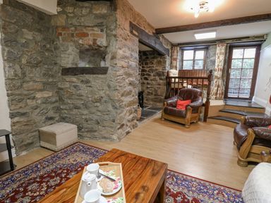 A living room with stone walls, leather chairs, a wooden table with tea set and a rug at The Searle in Nantmel near Rhayader