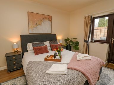 A bedroom with a bed with pillows bedside tables lamps and a window at The Searle in Nantmel near Rhayader