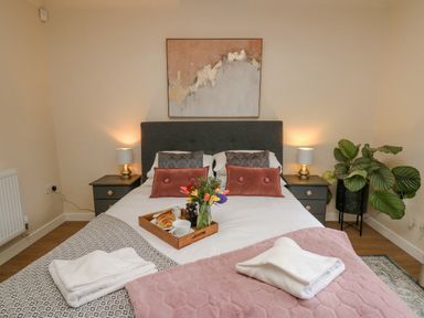 A bedroom with a double bed two bedside tables with lamps a plant and a tray with breakfast at The Searle in Nantmel near Rhayader
