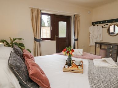 A bedroom with a bed a tray with breakfast by a window with curtains and a door at The Searle in Nantmel near Rhayader