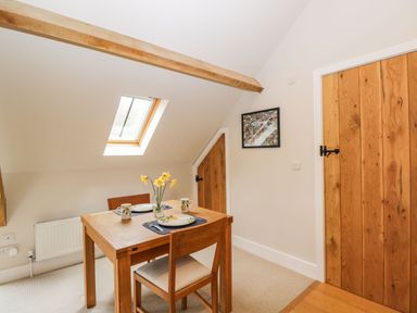 A dining area with a wooden table set for two under a skylight window at Avon Turn View in Alderbury