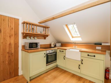 A kitchen with wooden counters green cabinets a microwave oven toaster kettle and a sink under a skylight at Avon Turn View in Alderbury