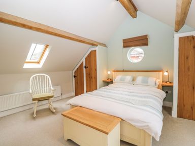 A bedroom with a bed a wooden chest a rocking chair and skylight window at Avon Turn View in Alderbury