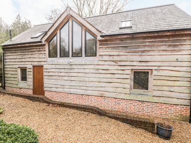 An exterior view of a wooden house with brick foundation and gravel pathway at Avon Turn View in Alderbury