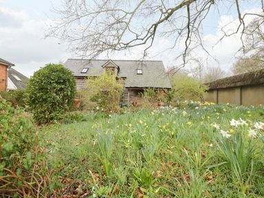 A garden with flowers and bushes in front of a house with a slate roof at Avon Turn View in Alderbury