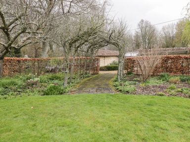 A garden pathway with a metal arbor surrounded by plants and trees at Avon Turn View in Alderbury