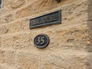 A stone wall with a sign reading Riseholme and a house number 35 plaque at Riseholme in Ebberston