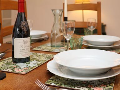 A dining table set with white plates wine bottle glasses and a water carafe at Riseholme in Ebberston