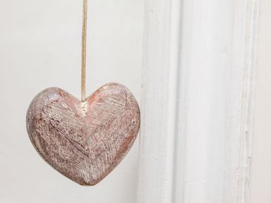 A wooden heart hanging by a string next to a white painted wall at Riseholme in Ebberston