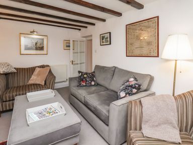 A living room with sofas, an ottoman, wall art, and a floor lamp at Riseholme in Ebberston