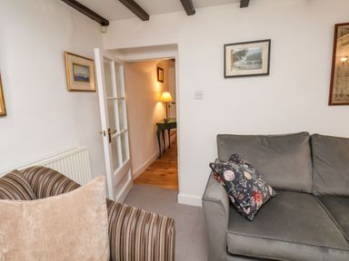 A living room with a grey sofa and a striped armchair a hallway with a table and lamp at Riseholme in Ebberston