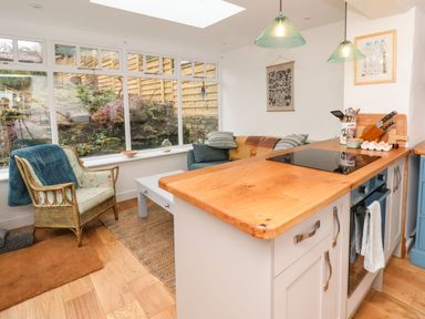 A kitchen area with a wooden countertop and seating area by large windows at Riseholme in Ebberston