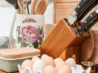 Kitchen counter with eggs in a white holder wooden knife block with knives wooden utensils in a floral container and cutting board at Riseholme in Ebberston