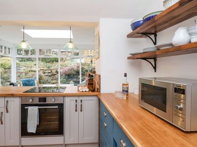 A kitchen with wooden countertops microwave oven stove and large windows overlooking a garden at Riseholme in Ebberston