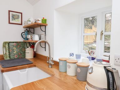 A kitchen countertop with a sink a kettle storage jars and cups by a window at Riseholme in Ebberston