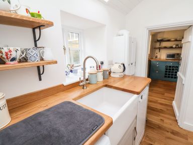 A kitchen corner with a white sink wooden countertop and shelves with mugs at Riseholme in Ebberston