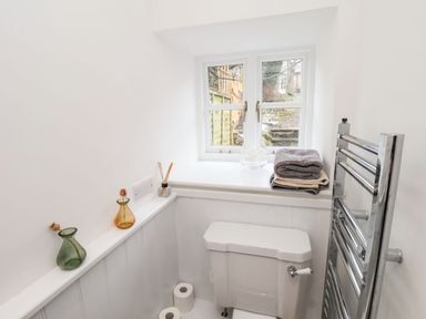 A toilet beneath a window with folded towels on the sill and chrome towel rack in a bathroom at Riseholme in Ebberston