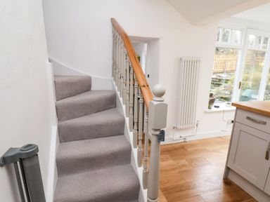 A carpeted staircase with wooden handrail next to a kitchen area with wooden floor and a window at Riseholme Ebberston