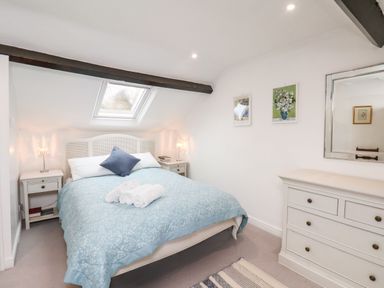 A bedroom with a bed with blue bedding and rolled towels a dresser with a mirror and two framed pictures at Riseholme in Ebberston