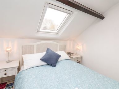 A bedroom with a double bed a blue patterned duvet a skylight window and bedside tables with lamps at Riseholme in Ebberston