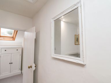A hallway with a white door a framed mirror on the wall and a cabinet under a skylight window at Riseholme in Ebberston