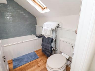 A bathroom with a bathtub under a skylight window a toilet and towels on a heated towel rail on a wooden floor at Riseholme in Ebberston