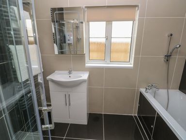 A bathroom with a sink cabinet mirror window shower and bathtub at Timaru in Lamphey