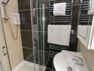 A bathroom with a shower enclosure sink and towel rail with towels at Timaru in Lamphey