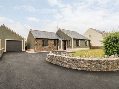 A single story house with a stone front wall driveway and garage at Timaru in Lamphey