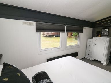 A bedroom with a bed next to two windows and a white wardrobe in 64 Penlan Holiday Park Cenarth