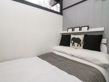 A bed with black and white pillows and a chevron blanket in a small bedroom at 64 Penlan Holiday Park in Cenarth