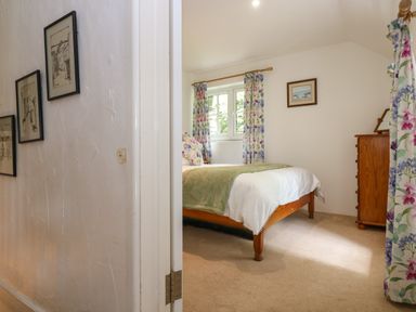 A bedroom with a wooden bed green bedding floral curtains and a wooden dresser at Byre in Trethin near Camelford