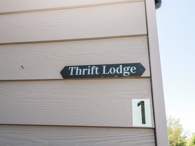 A sign on a beige wooden wall that says Thrift Lodge with the number 1 below it at Thrift Lodge in High Newton-by-the-Sea near Embleton