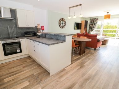 An open kitchen and living area with a countertop a dining table and a sofa at Thrift Lodge in High Newton-by-the-Sea near Embleton