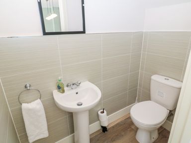A small bathroom with a sink a toilet a hand towel and a wall mirror at Thrift Lodge in High Newton-by-the-Sea near Embleton