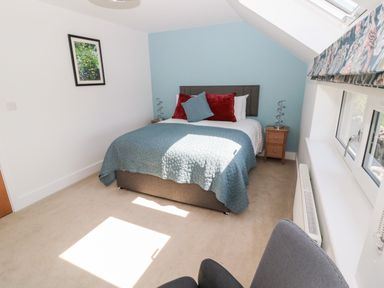A bedroom with a double bed with cushions and two bedside tables under a skylight window at Thrift Lodge in High Newton-by-the-Sea near Embleton