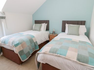 A bedroom with two single beds side by side each with a checkered blanket two pillows and a bedside table at Thrift Lodge in High Newton-by-the-Sea near Embleton