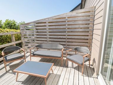 An outdoor wooden deck with two chairs a bench and a coffee table at Thrift Lodge in High Newton-by-the-Sea near Embleton