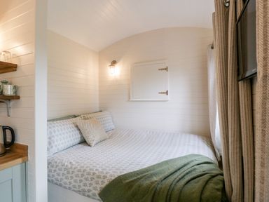 A small bedroom with a bed covered in patterned bedding and a green blanket at Beech in Kemble