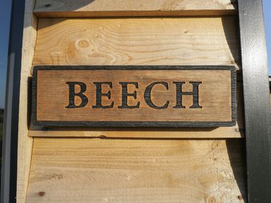 A wooden sign with the word BEECH mounted on a light wooden wall at Beech in Kemble