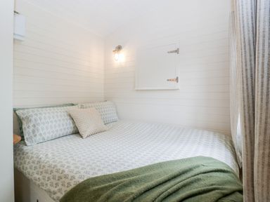 A bedroom with a bed covered in patterned bedding and a green throw blanket at Hazel in Kemble