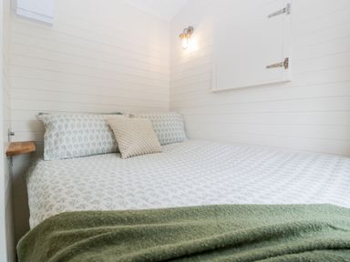 A bedroom with a bed covered in floral bedding and a green blanket at Hazel in Kemble