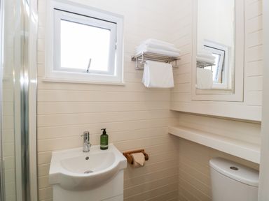 A small bathroom with a sink toilet window and towels on a rack at Hazel in Kemble