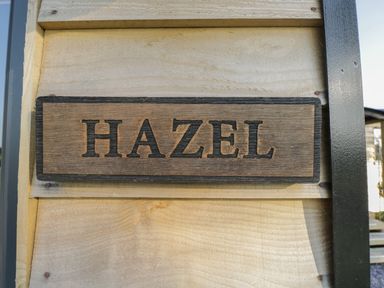 A wooden sign with the word HAZEL mounted on a light wooden wall at Hazel in Kemble