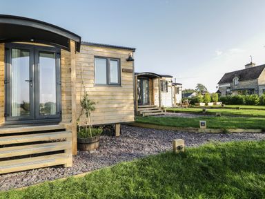 Wooden cabins with steps and stone pathways on grassy land at Hazel in Kemble